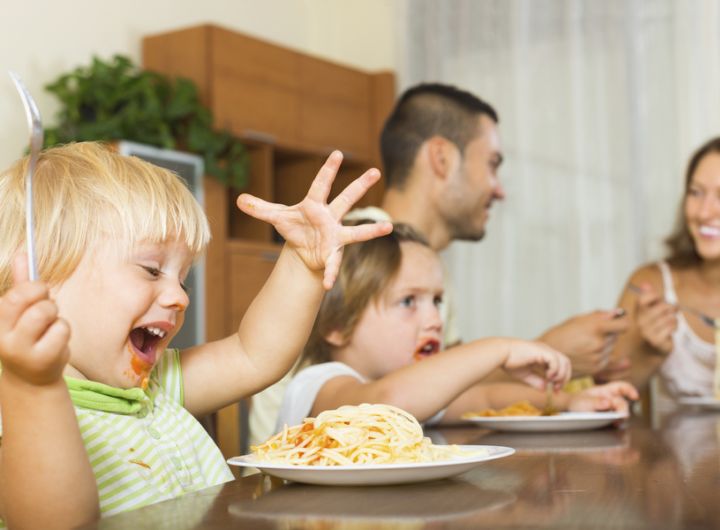 family around the dinner table eating spaghetti