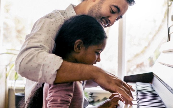 Dad teaches child to play piano